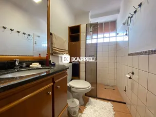 Banheiro com box de vidro e bancada de madeira.