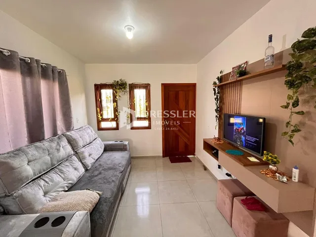 Sala de estar com sofá e janelas no imóvel.